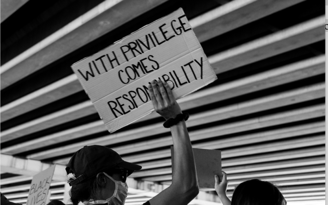 A person in a protest, holding a sign that reads "With privilege comes responsibility."